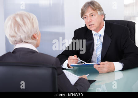 Mature Businessman Discussing With Businesswoman In Meeting Stock Photo