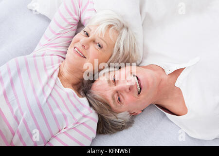 Happy Senior Couple Lying Side By Side On Bed Stock Photo