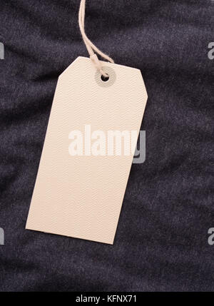 Close up of blank paper label tag on dark gray garment Stock Photo