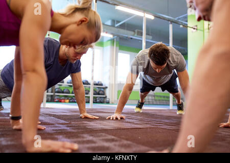 group of people doing straight arm plank in gym Stock Photo