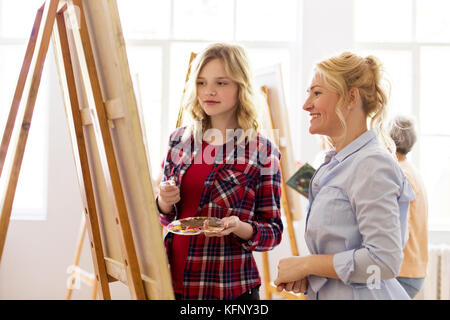 artists discussing painting on easel at art school Stock Photo