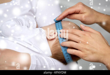 close up of hands with tape measuring baby head Stock Photo