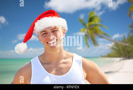 happy young man in santa hat on beach at christmas Stock Photo