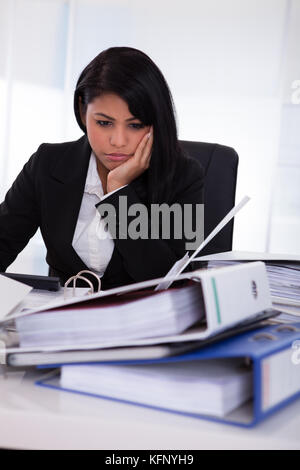 Portrait Of Overworked Businesswoman Looking At Folder Stock Photo