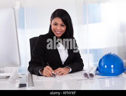 Portrait Of Female Architect Drawing Blueprint In The Office Stock Photo