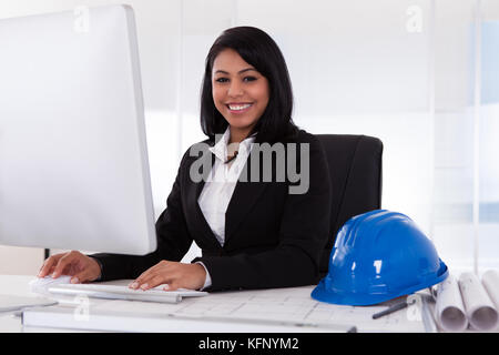 Happy Young Female Architect Using Computer In Office Stock Photo