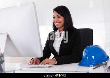 Happy Young Female Architect Using Computer In Office Stock Photo