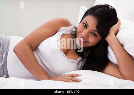 Portrait Of Young Happy Woman Lying On Bed Stock Photo