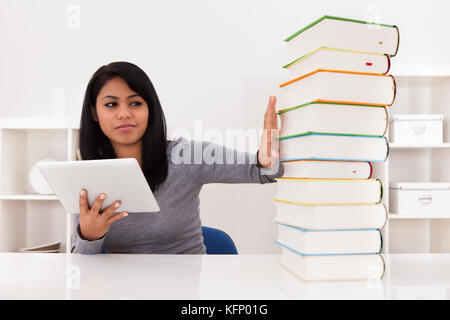 Young Woman Avoiding Books And Using Tablet At Home Stock Photo