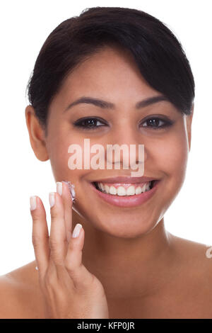 Young Woman Applying Cream On Her Face Over White Background Stock Photo