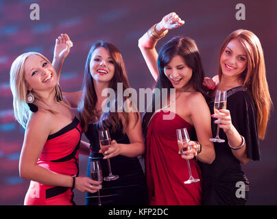Group of four stylish women standing in a row toasting with flutes of champagne Stock Photo