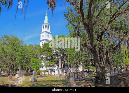 Spire main building and graveyard framed by Spanish moss-covered trees at the parish church of St. Helena in the historic district of downtown Beaufor Stock Photo