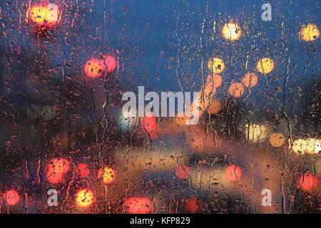 Raindrops on the windshield. Street traffic abstract light bokeh defocused light. Background. Stock Photo