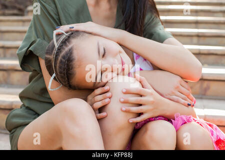 Little girl putting head on mother's knees Stock Photo