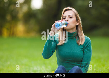 Young woman drinking water in park Stock Photo