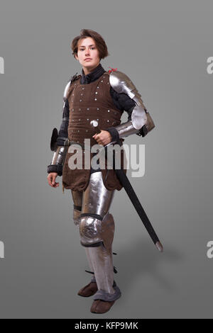 portrait of a medieval female knight in armour with sword isolated over grey background Stock Photo