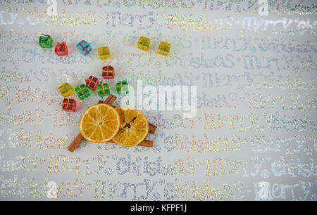 colorful Christmas food photography image with glass xmas presents for tree hanging decoration  cinnamon oranges with shiny wrapping paper background Stock Photo