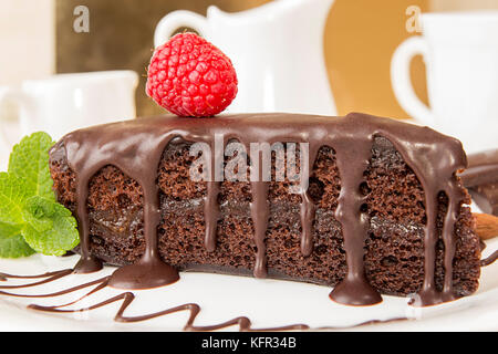 Sachertorte. Piece of sacher cake on white plate garnish with mint and raspberry. Austrian traditional dessert Stock Photo