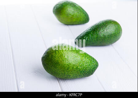 Three avocados on the white wooden table . Healthy living, diet, raw eating, vegetable fats concept background. Selective focus, space for text. Stock Photo