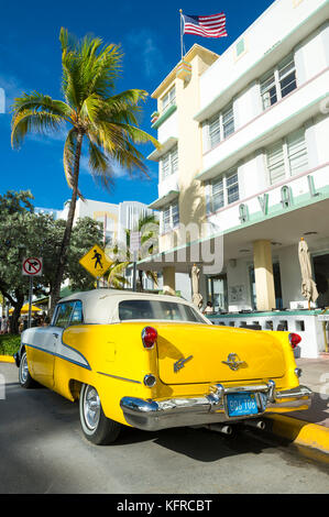 MIAMI - July 23, 2017: Classic vintage american car parked on Miami Beach's iconic Ocean Drive with backdrop of art-deco buildings and palm trees. Stock Photo