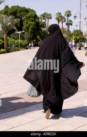 Marrakesh, Morocco, 14 October, 2017: A woman in black hijab walking in a strong sun in Marrakesh. Stock Photo