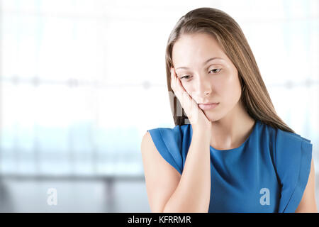 Sad and bored woman thinking about something, in a blue background Stock Photo