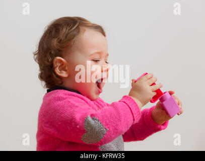 Toddler baby girl plays with soft rubber building blocks Stock Photo