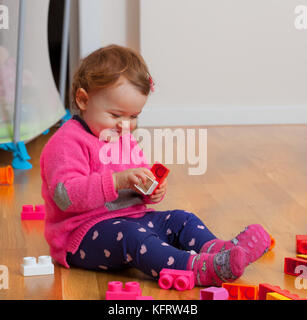 Toddler baby girl plays with soft rubber building blocks. Stock Photo