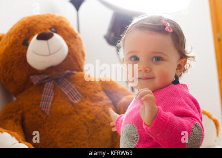 Toddler baby girl playing with big teddy bear during a photo shoot. Stock Photo