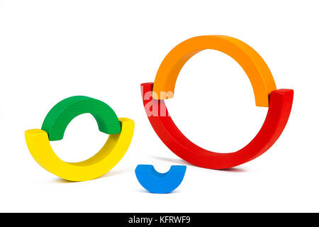 A wooden toy of seven different-colored arcs in the form of a rainbow on a white isolated background, the arcs are folded in the form of circles Stock Photo