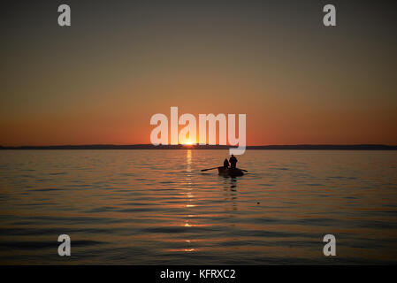Boat in the sea with two fishermen in it, nets in the sea. Sunset or sunrise Stock Photo