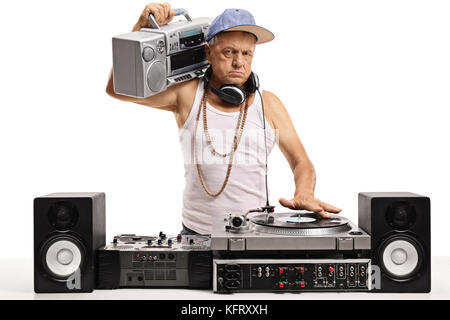 Angry elderly DJ with a boombox playing music on a turntable isolated on white background Stock Photo