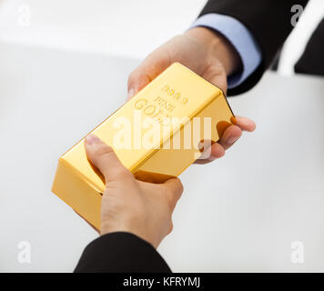 Close-up on hand of business people exchanging golden bar Stock Photo