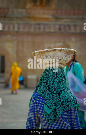 Jaipur, India - September 19, 2017: Portrait of unidentified woman carrying ain her head a basket while she is walking inside of the city in Amber Fort on the streets of Jaipur, India Stock Photo