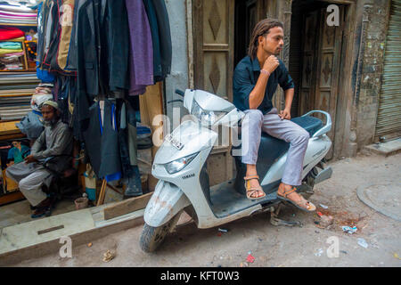 DELHI, INDIA - SEPTEMBER 25 2017: Unidentified man sitting over his motorcycle waiting in the streets in Paharganj, Delhi. Delhi is the 2nd most populous city in India after Mumbai Stock Photo