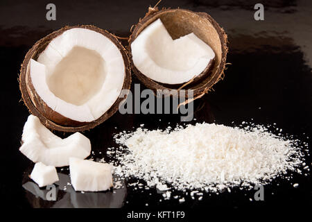 Half of coconut, pieces of coconut, coconut flakes on black background. Healthy food concept Stock Photo