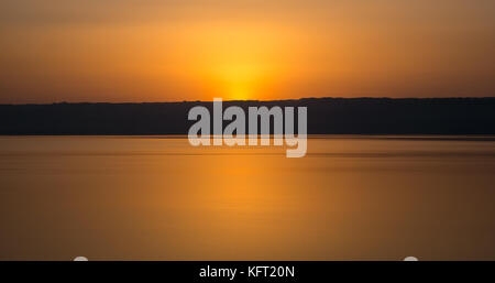 Minimalist orange sunset over the Dead Sea from Jordan shoreline, looking towards the West Bank, Middle East Stock Photo