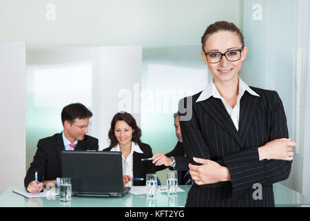 Corporate advancement and leadership concept with a confident smiling attractive businesswoman wearing glasses standing with her arms folded Stock Photo