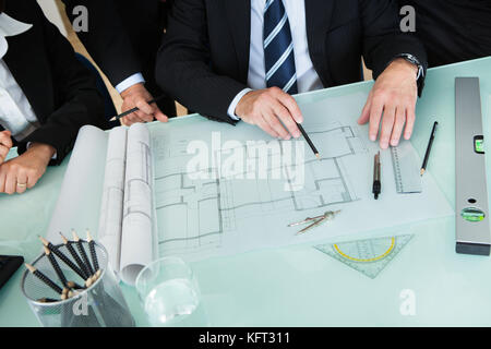 Cropped high angle view of the hands of a group of architects discussing a blueprint or architectural drawing laid out on a tabletop Stock Photo
