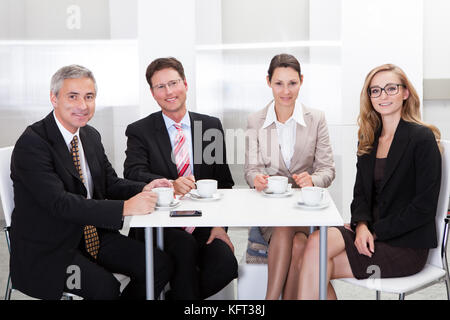 Business executives sitting around a table enjoying a relaxing cup of coffee together during a break Stock Photo