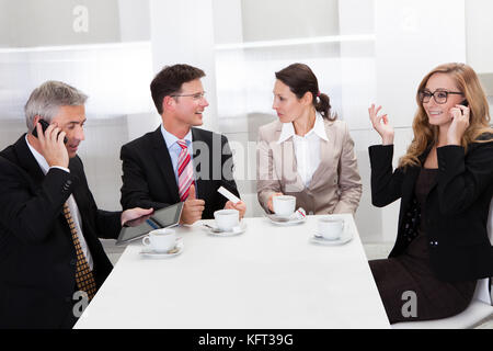 Business executives sitting around a table enjoying a relaxing cup of coffee together during a break Stock Photo