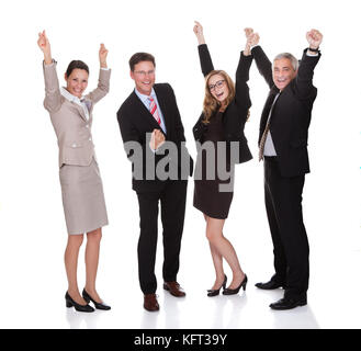Four excited diverse professional businesspeople celebrating a success laughing and raising their arms in the air isolated on white Stock Photo