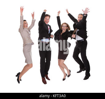 Four diverse professional business partners jumping for joy with their arms raised shouting in jubilation isolated on white Stock Photo