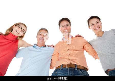 Two happy attractive middle aged couples standing arm in arm looking down at the camera Stock Photo