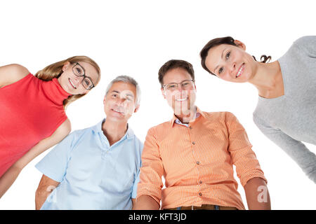 Two happy attractive middle aged couples standing arm in arm looking down at the camera Stock Photo