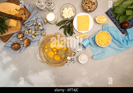 Overhead of ingredients frittata quishe vegeterian diet meal. Eggs in bowl, quail eggs, milk, cheese mozzarella, gouda, tomato, spinach, mushrooms, ch Stock Photo