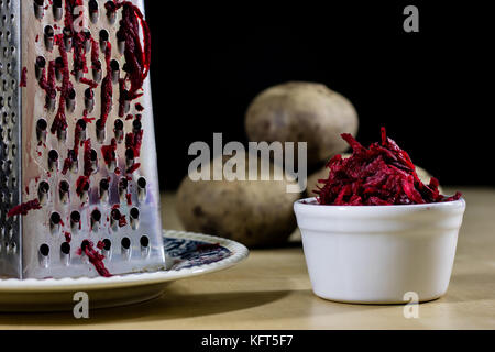 Beetroots grated on shavings. Wooden dining table. Black background. Stock Photo