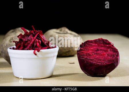 Beetroots grated on shavings. Wooden dining table. Black background. Stock Photo