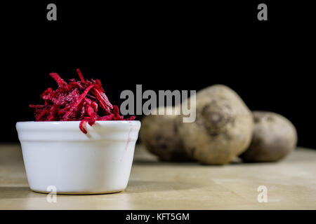 Beetroots grated on shavings. Wooden dining table. Black background. Stock Photo