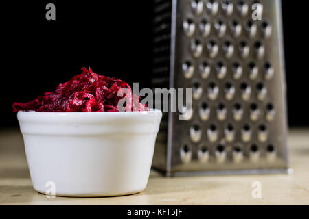 Beetroots grated on shavings. Wooden dining table. Black background. Stock Photo